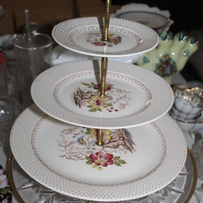 Sale Photo Thumbnail #28: Vintage three-tier floral ceramic serving tray with a brass center spindle, featuring a polka dot rim and central botanical motifs.