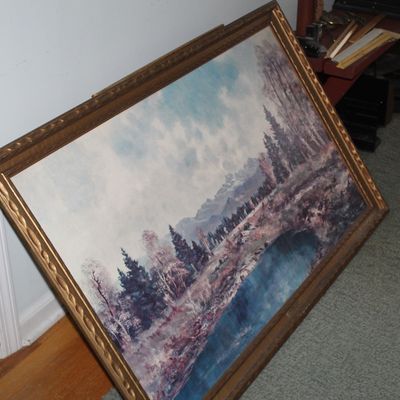 Sale Photo Thumbnail #35: Large framed landscape painting depicting a serene lake surrounded by pine trees and mountains, set in an ornate carved wood frame.