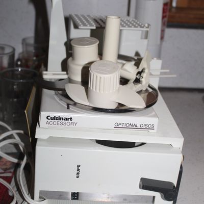 Sale Photo Thumbnail #72: Vintage white Krups kitchen appliance with an assortment of food processor blades and Cuisinart accessories.