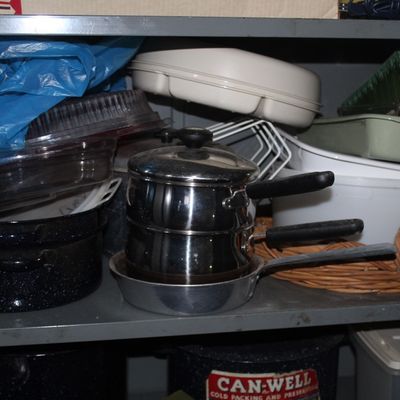 Sale Photo Thumbnail #104: Metal shelving unit filled with assorted kitchenware, including stainless steel double boilers, enamelware pots, and plastic storage containers.