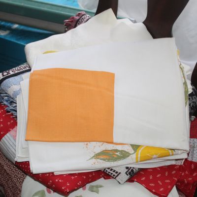 Sale Photo Thumbnail #62: Stack of vintage linens, tea towels, and textiles resting on a wooden chair.