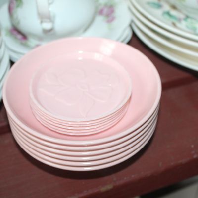 Sale Photo Thumbnail #15: Stacks of light pink plastic or glass saucers and small floral-embossed coasters, displayed alongside floral vintage china.
