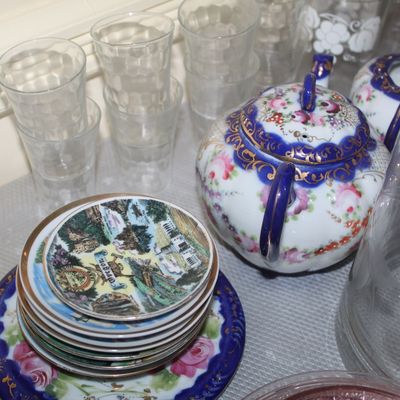 Sale Photo Thumbnail #54: Collection of vintage glassware and porcelain, including a hand-painted floral teapot with cobalt and gold accents, souvenir miniature plates, and stacked pressed glass tumblers.
