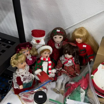 Selection of vintage Christmas decor, including porcelain dolls in festive attire, Santa Claus figures, and a lighted ceramic Christmas...