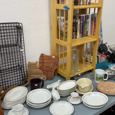 Vintage Henry Thiele's restaurant dishware alongside various DVDs, glassware, wooden cutting boards, and kitchen items.
