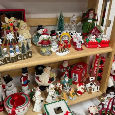 Christmas decor display featuring vintage and modern Santa figurines, snowmen, nutcrackers, Coca-Cola snow globes, porcelain angels, and...