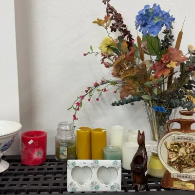 Assorted tabletop decor, featuring a Loyal Order of Moose decanter, a floral pedestal bowl, pillar candles, and a faux floral arrangement...