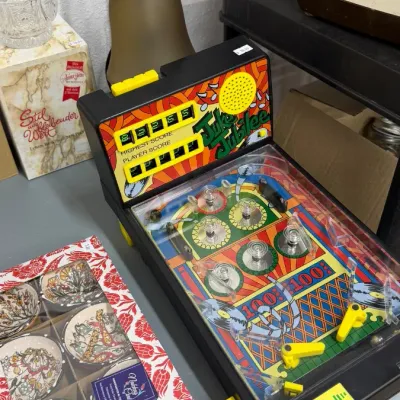Vintage Juke Jubilee tabletop pinball game displayed alongside a boxed set of Turkish ceramic bowls and a frosted glass pendant lamp.