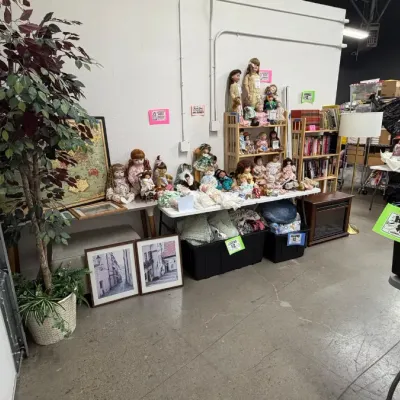Porcelain dolls in vintage dresses, framed artwork, artificial house plants, and an electric fireplace heater.