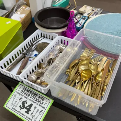 Assorted gold-tone and silver-tone flatware, decorative souvenir spoons, and kitchen utensils.