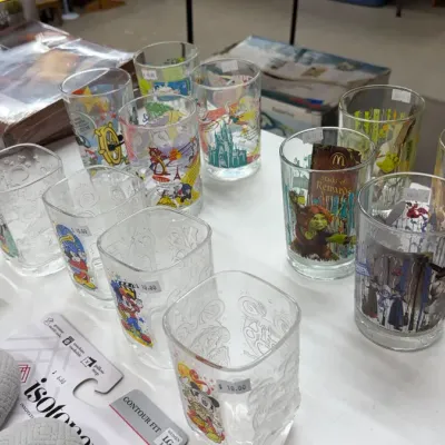 Vintage character promotional drinking glasses, including Disney, Star Wars, and Shrek McDonald's glasses, displayed alongside...