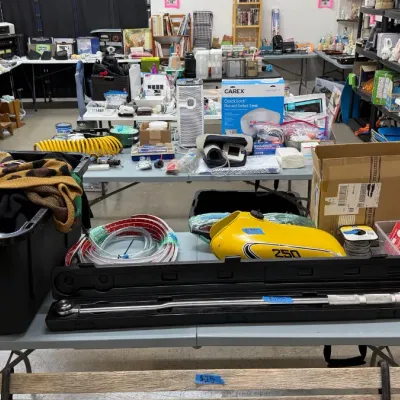 A torque wrench in a black hard case, a yellow Yamaha 250 motorcycle gas tank, apparel in a black bin, medical supplies, vintage...