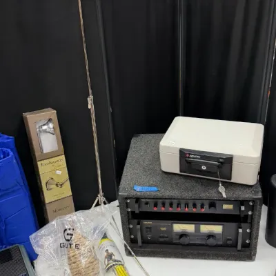 A folding metal music stand, a Sentry lock box, a rack-mounted audio amplifier and mixer in a carpeted case, a framed Thomasville picture...
