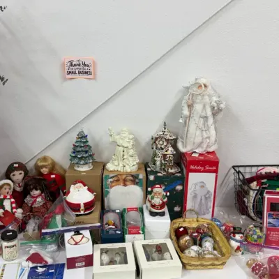 Christmas decorations, including Santa figurines, ceramic trees, vintage-style dolls, ornaments in a wicker basket, boxed holiday items,...