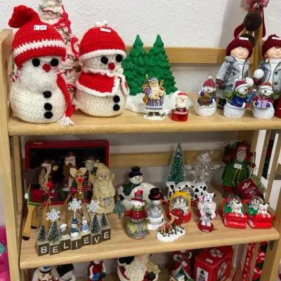 Christmas decor and figurines, including handcrafted crocheted snowmen, ceramic Santas, bottle brush trees, and snow globes.