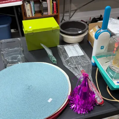 A vintage Suzy Homemaker Pop Corn Maker, woven placemats, bright green recipe box, glass storage jar, and various household and kitchen...