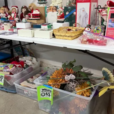 Selection of Christmas and holiday decorations, including porcelain dolls, Santa figures, wreaths, garden stakes, and boxed ornaments.