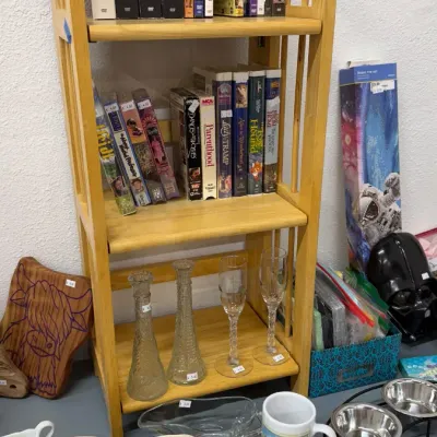DVD box sets, VHS tapes, glass stemware, and assorted home goods including ceramic serving dishes, a mug, and pet bowls.
