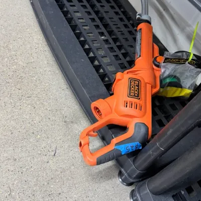 Black+Decker electric string trimmer with attached line accessory bag.