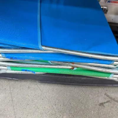 Folded aluminum lawn chairs with blue and green mesh fabric seating.