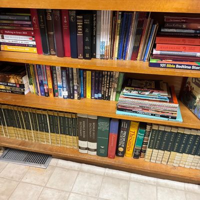 Sale Photo Thumbnail #55: Wooden bookcase filled with a wide collection of books, including religious texts, fiction paperbacks, children's stories, and multi-volume reference encyclopedias.