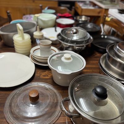 Sale Photo Thumbnail #49: Large assortment of vintage cookware and kitchen items, including stainless steel pots with glass lids, Pyrex bowls, ceramic dishes, and plastic stackable containers.