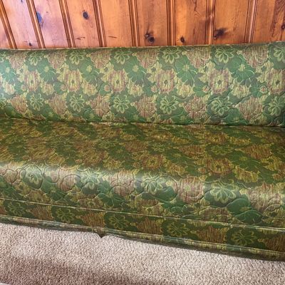Sale Photo Thumbnail #3: Vintage 1970s sofa featuring green and brown floral jacquard quilted upholstery, set against wood paneling.