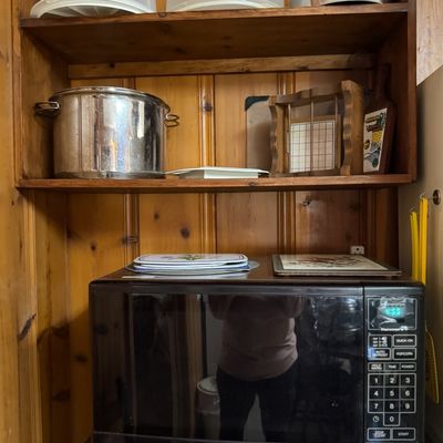 Sale Photo Thumbnail #48: Black Kenmore countertop microwave oven positioned below wooden shelves holding kitchenware and baking supplies.