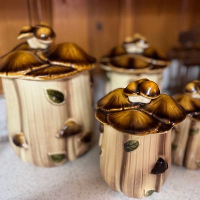 Sale Photo Thumbnail #18: Vintage four-piece ceramic mushroom canister set with tree stump bases and brown mushroom lids, circa 1970s.