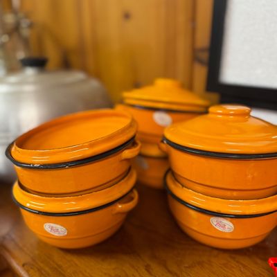 Sale Photo Thumbnail #51: Set of vintage bright orange enamelware lidded bowls and cookware pieces, featuring black rim trim and side handles.