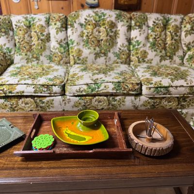 Sale Photo Thumbnail #13: Vintage 1970s floral upholstered sofa in green and yellow tones paired with a dark wood coffee table displaying mid-century accessories.