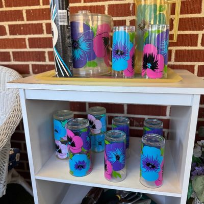 Sale Photo Thumbnail #34: Vintage retro acrylic drinkware set featuring colorful floral pansy motifs, including pitchers, tumblers, and an ice bucket arranged on a white shelf.