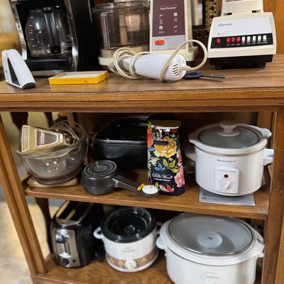 Sale Photo Thumbnail #56: Wooden kitchen cart filled with small appliances including slow cookers, a Mr. Coffee maker, vintage Osterizer blender, food processor, and a toaster.