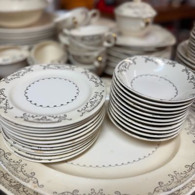 Sale Photo Thumbnail #15: Vintage dinnerware service with black delicate lace and scroll motifs, featuring stacks of plates, bowls, platters, and teacups.
