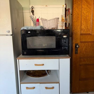 Sale Photo Thumbnail #14: Black GE countertop microwave sitting on a white laminate microwave cart 