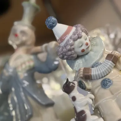 Sale Photo Thumbnail #77: Lladro-style glazed porcelain clown figurine featuring a child clown playing an accordion with a small dog at their feet.