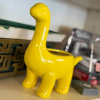Sale Photo Thumbnail #66: Bright yellow glossy ceramic dinosaur planter in good condition.