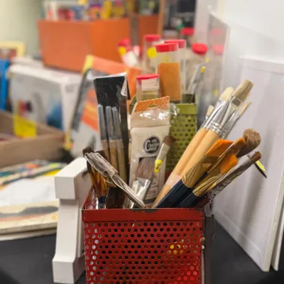 Sale Photo Thumbnail #72: Collection of assorted art supplies, including paintbrushes organized in perforated metal caddy containers.