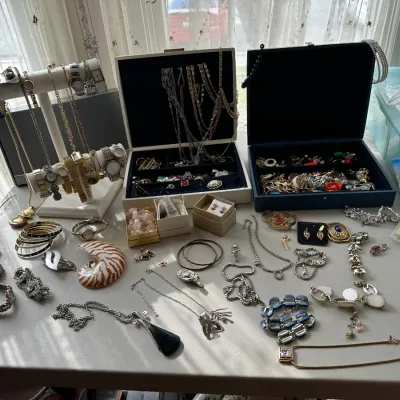 Large assortment of vintage costume jewelry, wristwatches, and jewelry boxes, displayed on a table.