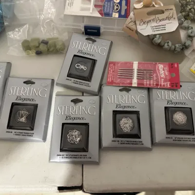 Sale Photo Thumbnail #4: Collection of jewelry-making supplies including Sterling Elegance sterling silver chains and clasps in original packaging, yarn needles, and loose gemstone beads.