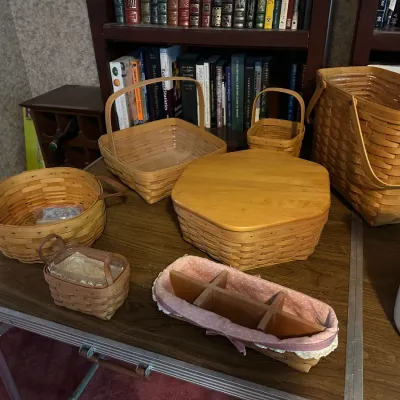 Collection of woven Longaberger style baskets in various shapes and sizes, including a lidded pie basket and a caddy with fabric liner.