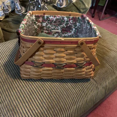 Longaberger woven wood basket featuring dual handles, decorative red trim with brass accents, and a floral fabric liner.