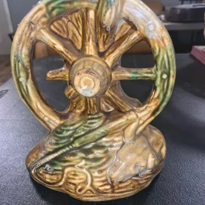 Vintage ceramic wagon wheel sculpture with a drip glaze finish in shades of brown and green.