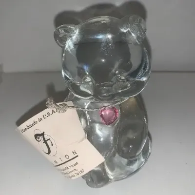 Fenton clear glass teddy bear figurine wearing a necklace with a pink heart pendant, featuring the original manufacturer's paper tag.