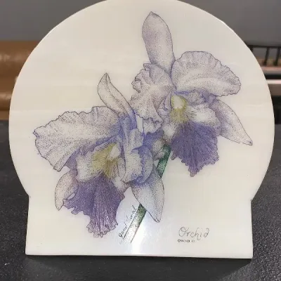Arched stone art plaque featuring a stippled illustration of purple orchids, signed Janet Vancil and dated 1997.