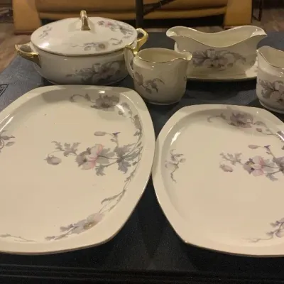 Vintage fine china serving set featuring a floral pattern with gold trim, including platters, creamer, gravy boat, and a covered...