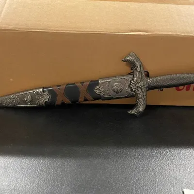 Ornate fantasy display dagger featuring an embossed metal pommel, sculpted crossguard, and a leather-look sheath with decorative fittings.
