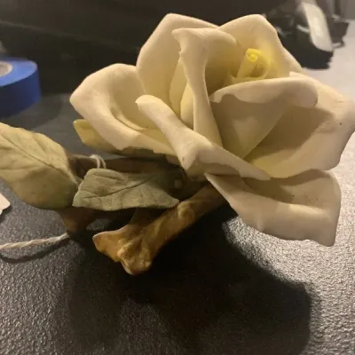 Handcrafted porcelain yellow rose figurine mounted on a stem with leaves, in good vintage condition.
