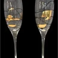 Pair of modern champagne flutes featuring gold leaf and fine black thread-like swirls on clear glass, appearing in excellent condition...
