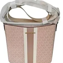 Blush pink Michael Kors logo canvas bucket handbag featuring a vertical center stripe, gold-tone hardware, and protective wrapping on the...
